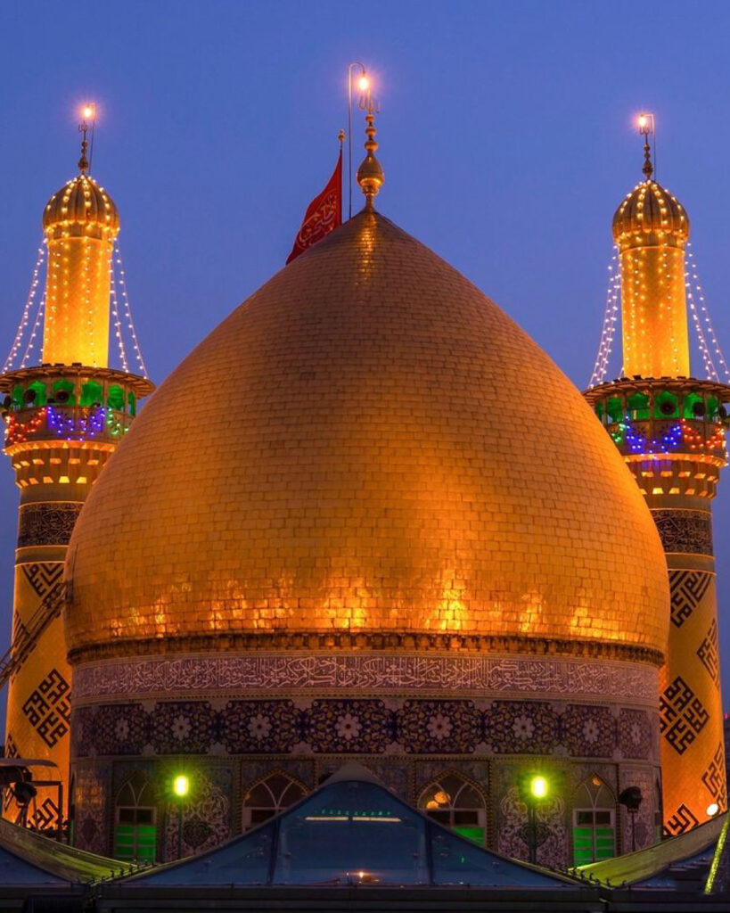 Night view of the Imam Hussain Shrine in Karbala, Iraq, with the golden dome and minarets glowing and thousands of pilgrims gathered for prayers and mourning.