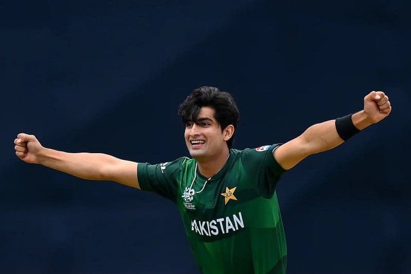 Pakistani fast bowler in action during a T20 match, delivering a fast ball with the crowd watching.