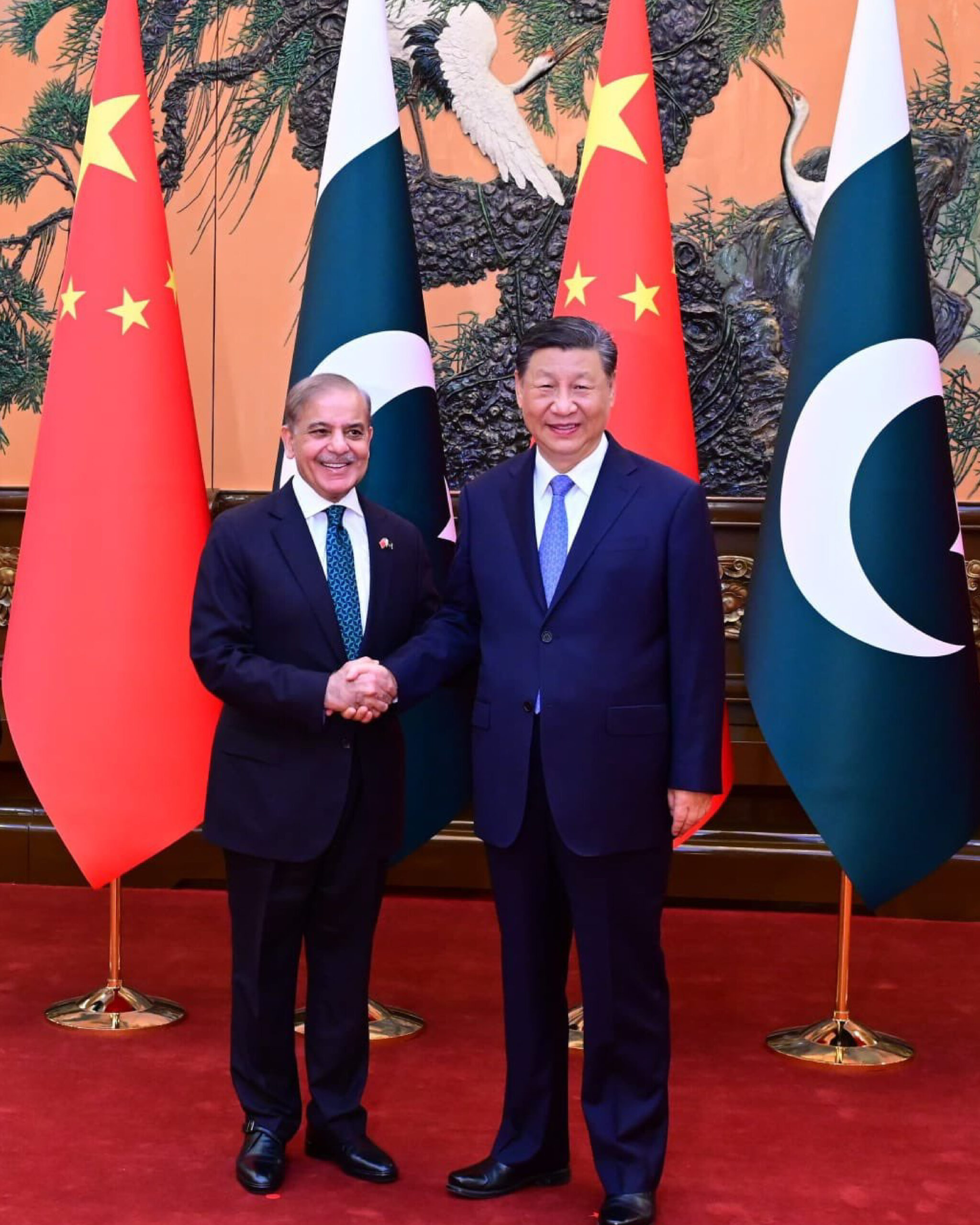 Pakistani and Chinese officials shake hands before their national flags, representing a $3.3 billion loan agreement to boost Pakistan’s foreign exchange reserves