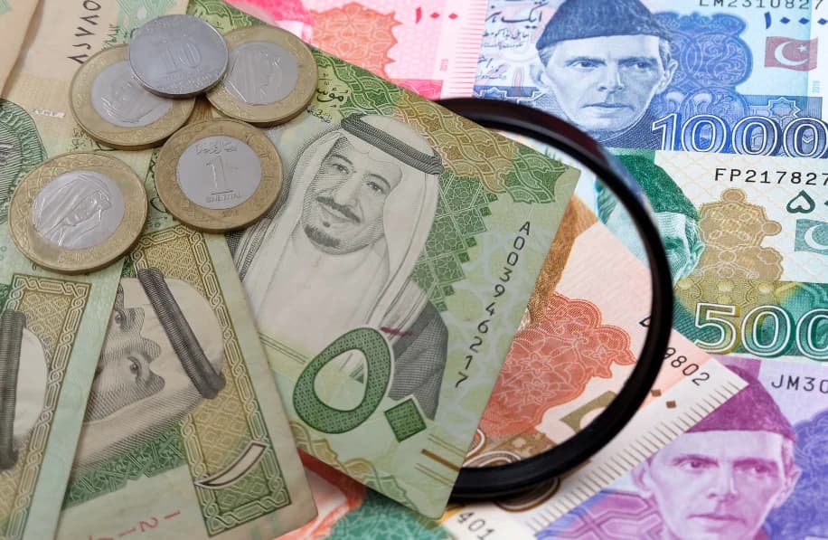 Saudi Riyal and Pakistani Rupee notes on a counter with a digital display of current exchange rates, representing the SAR to PKR market on June 3, 2025