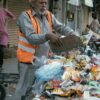 "Pakistani sanitation worker in orange vest collecting waste during Lahore Eid clean-up record operation 2025"