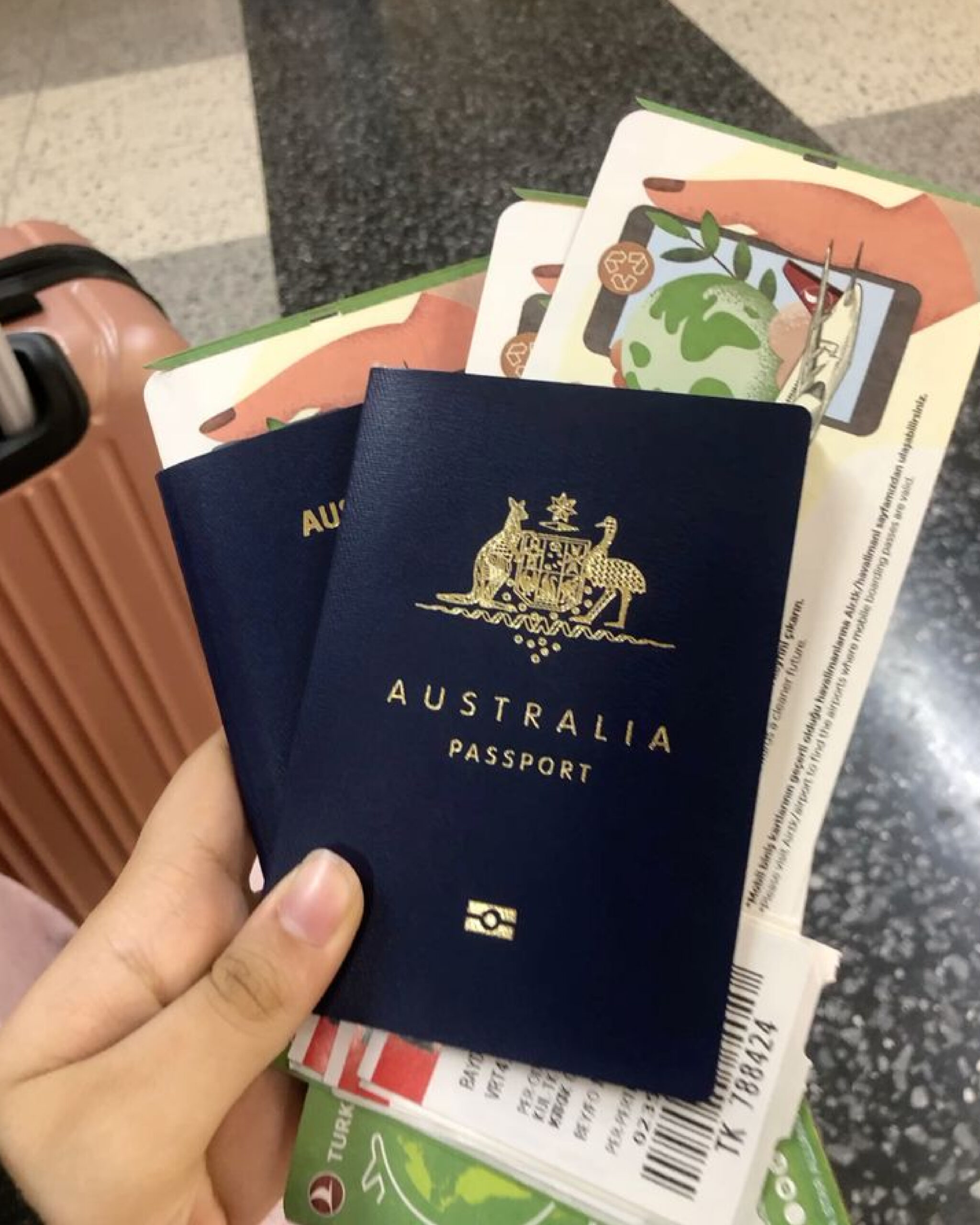 Hand holding an Australian passport and boarding pass at an airport, symbolizing the journey to Australia on a 2025 working holiday visa.