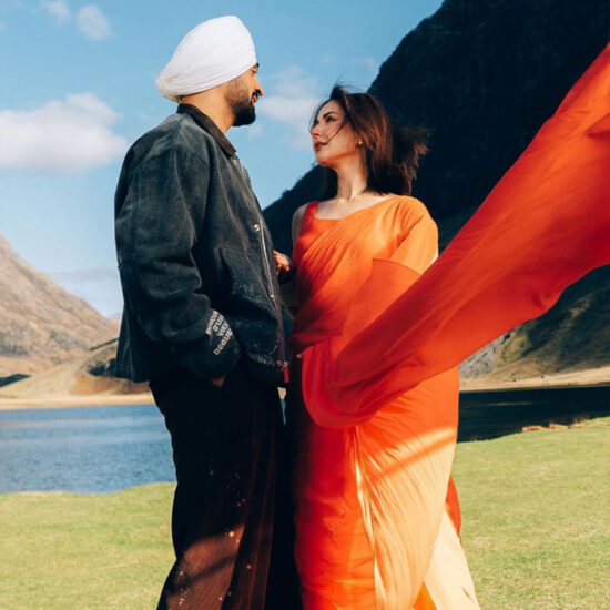 Diljit Dosanjh performing a dramatic scene in the mountains for Sardaar Ji 3, surrounded by vibrant costumes and cinematic energy.