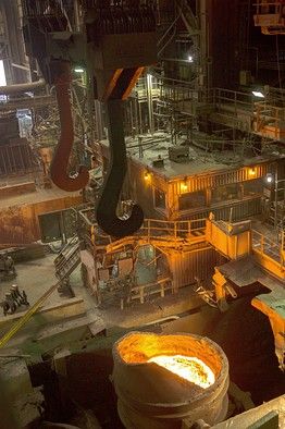 Interior view of a modern steel mill in Karachi with Russian and Pakistani engineers collaborating and molten steel being processed.