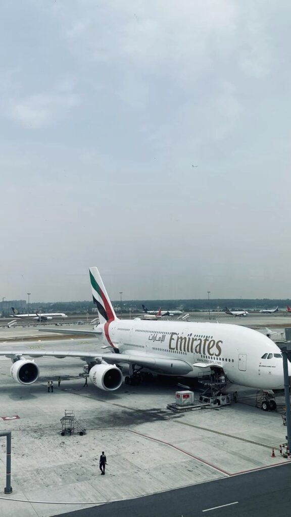 Emirates Airbus A380 flying above clouds at sunrise, representing luxury and global leadership.