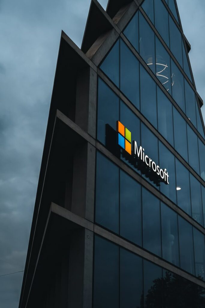 AI-powered robots and human employees working together in a modern office, with empty desks representing recent Microsoft layoffs and a backdrop of digital servers and neural network visuals.